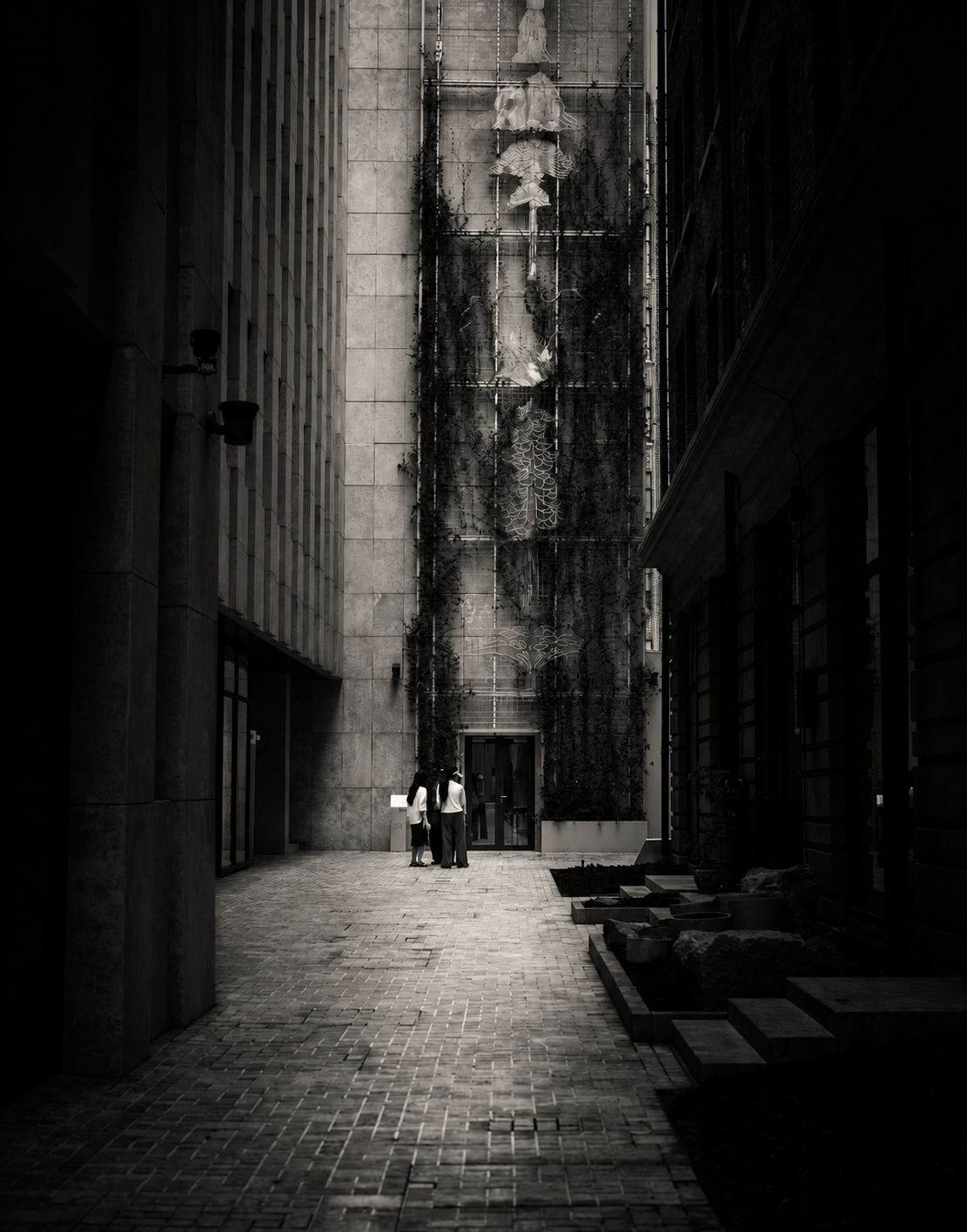 Two small figures at the end of a shadowed urban passage