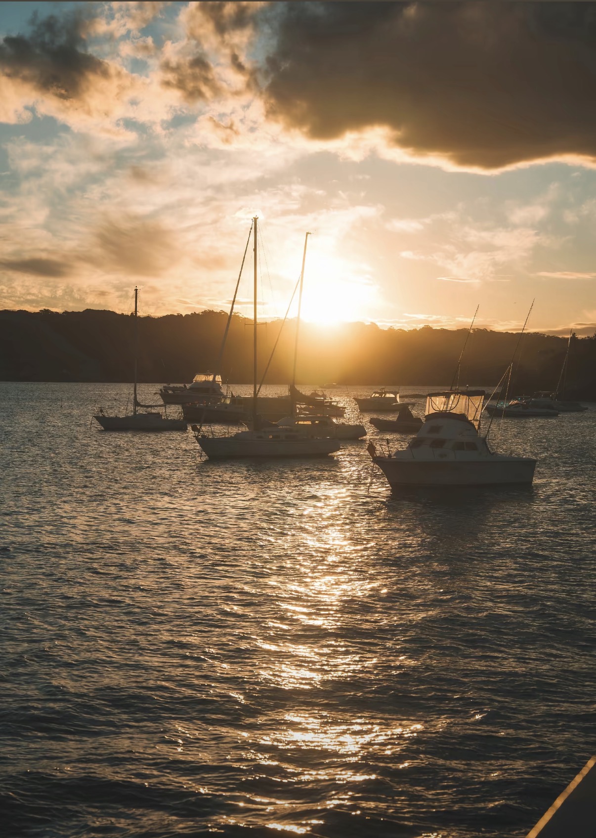 Boats resting in a harbour beneath a glowing sunset