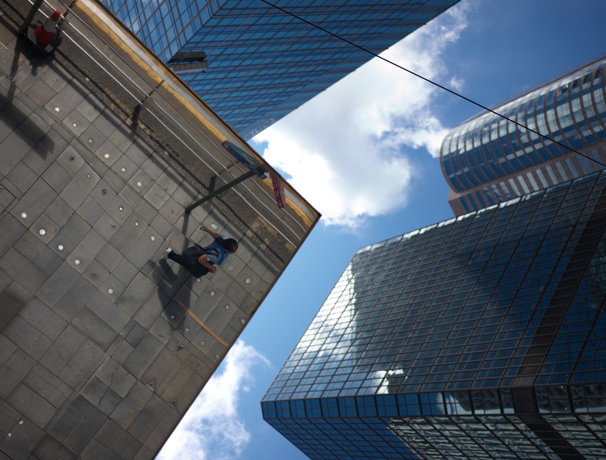 A pedestrian framed by modern buildings and an open blue sky