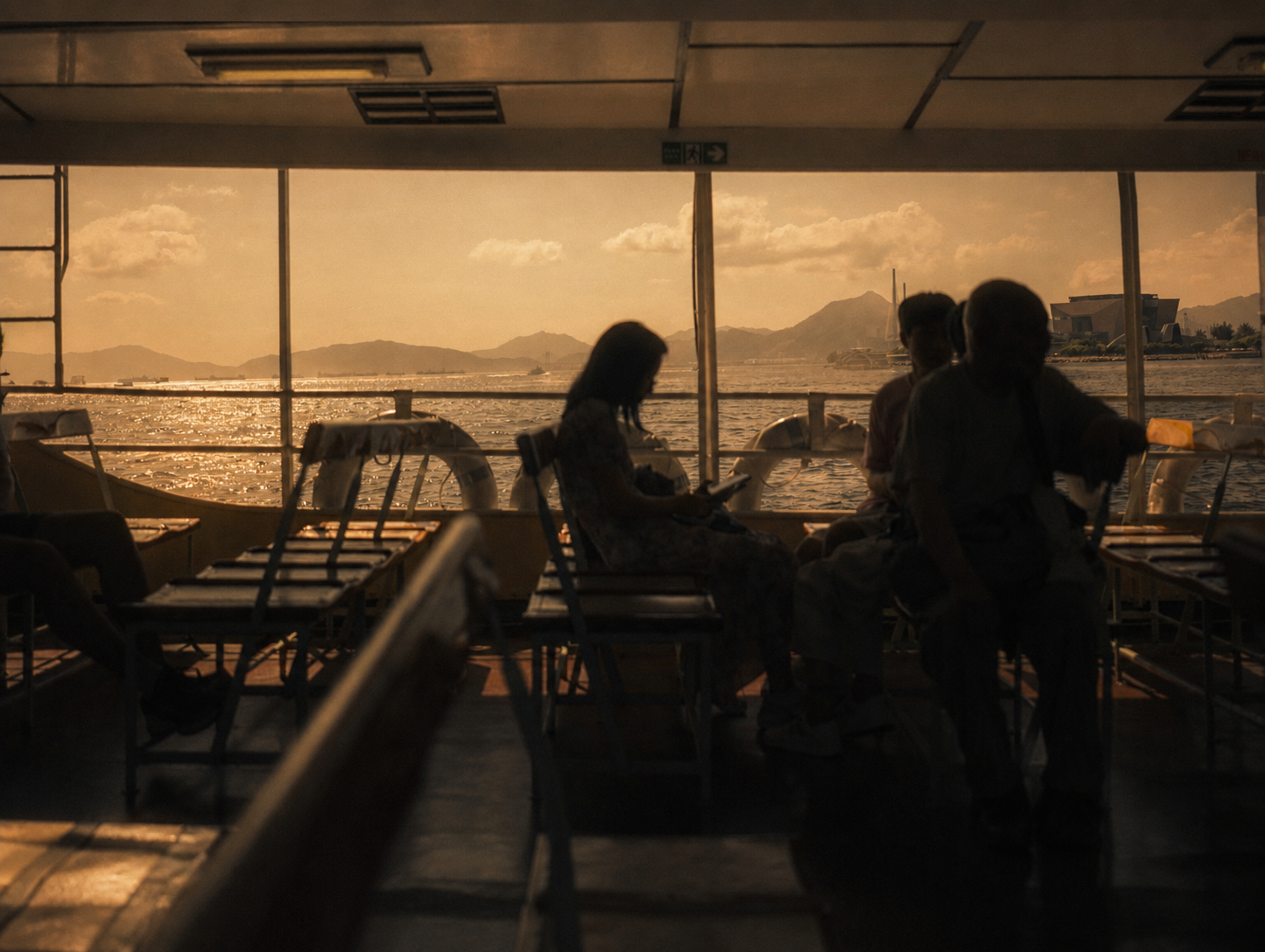 Passengers silhouetted inside a ferry against warm evening light