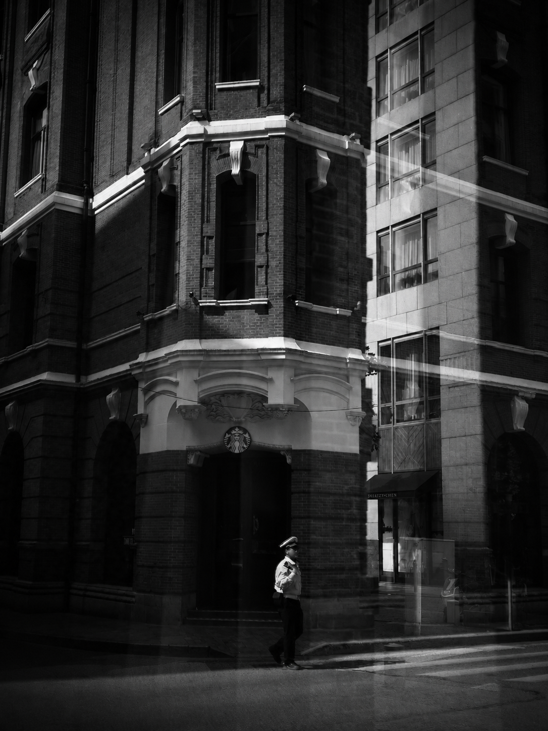 A lone guard in a patch of light beneath a dark historic facade