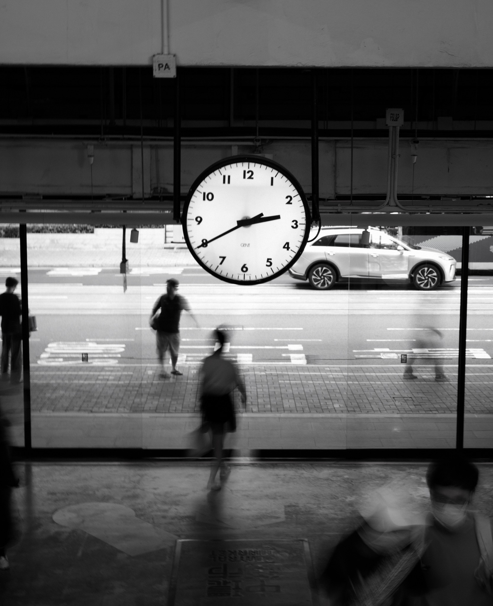 A large station clock above blurred commuters